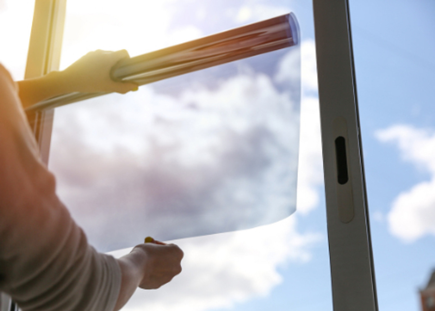 Technician applying solar control window film to a large glass window